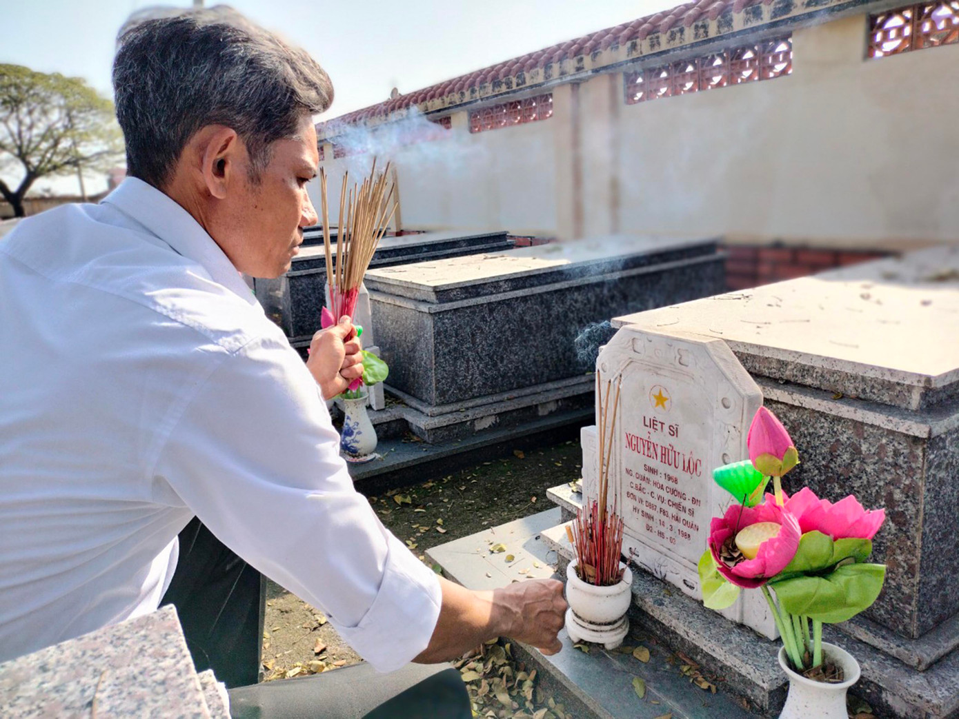 Anh Trần Văn Hùng và đồng nghiệp thắp hương, chăm sóc những ngôi mộ gió liệt sĩ Gạc Ma ở nghĩa trang liệt sĩ TP Đà Nẵng. Ảnh: Nguyễn Thành