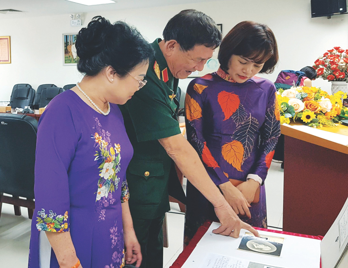 Anh hùng Phạm Tuân trao đổi với bà Nguyễn Minh Thủy (trái) về huy hiệu có chân dung Chủ tịch Hồ Chí Minh do cố hoạ sĩ Bùi Trang Chước vẽ. Ảnh: Kiến Nghĩa