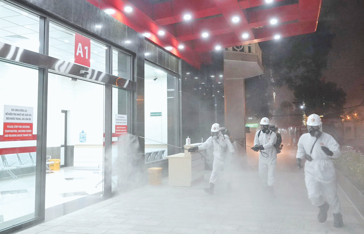 Chiến sĩ phòng hóa khử trùng, tiêu độc COVID-19 tại Bệnh viện Bạch Mai, tối 28/3/2020. ẢNH: NGUYỄN MINH