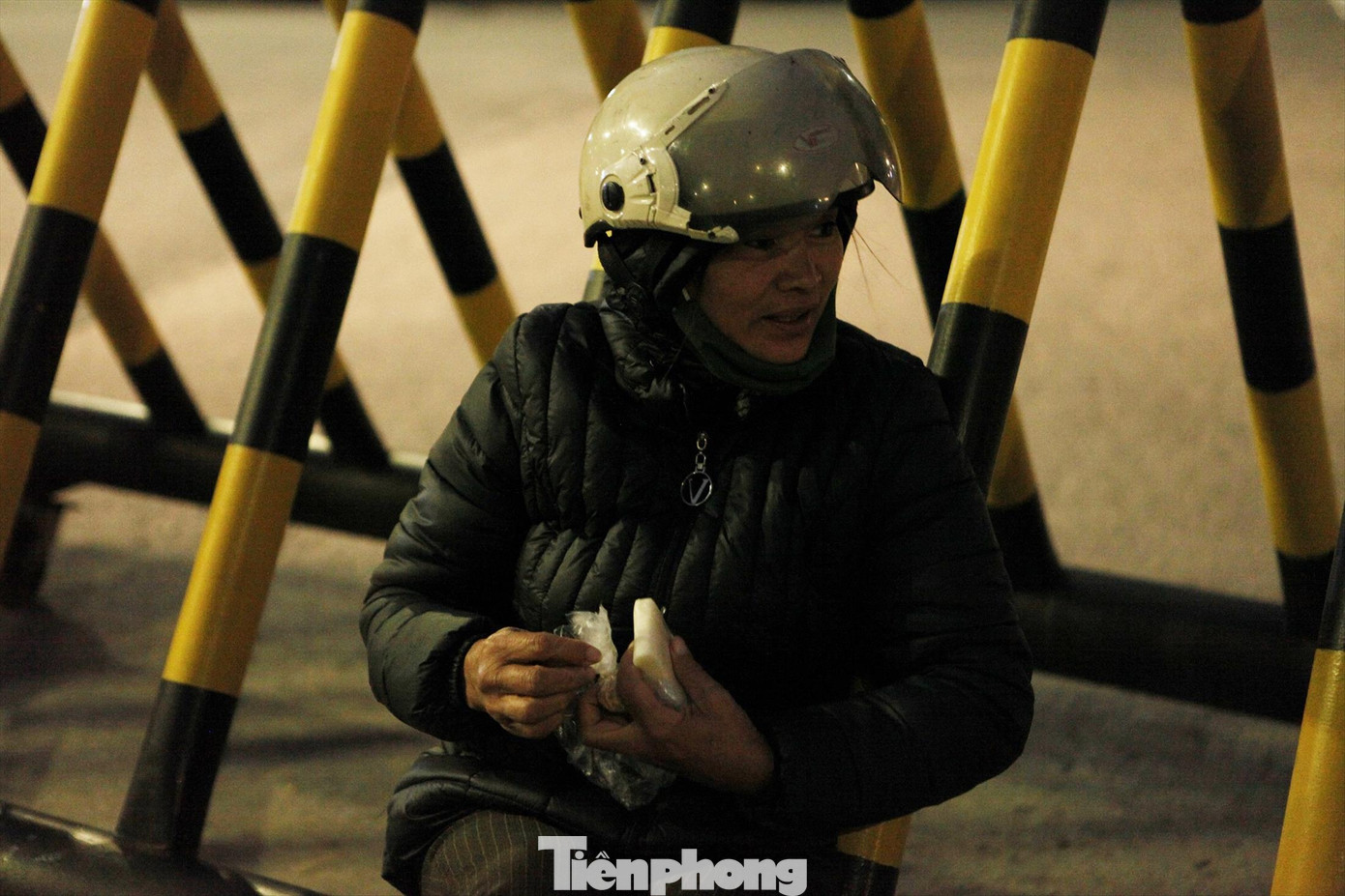 Chị Nguyễn Thị Mười tranh thủ ăn ít xôi lót dạ thay cho bữa tối trong lúc đợi khách