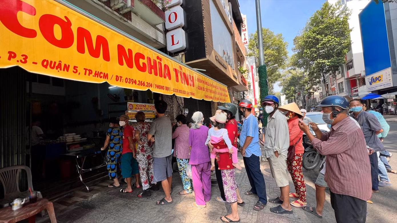 Người lao động xếp hàng mua cơm trợ giá 10.000 đồng và nhận cơm miễn phí từ “Trạm cơm nghĩa tình”