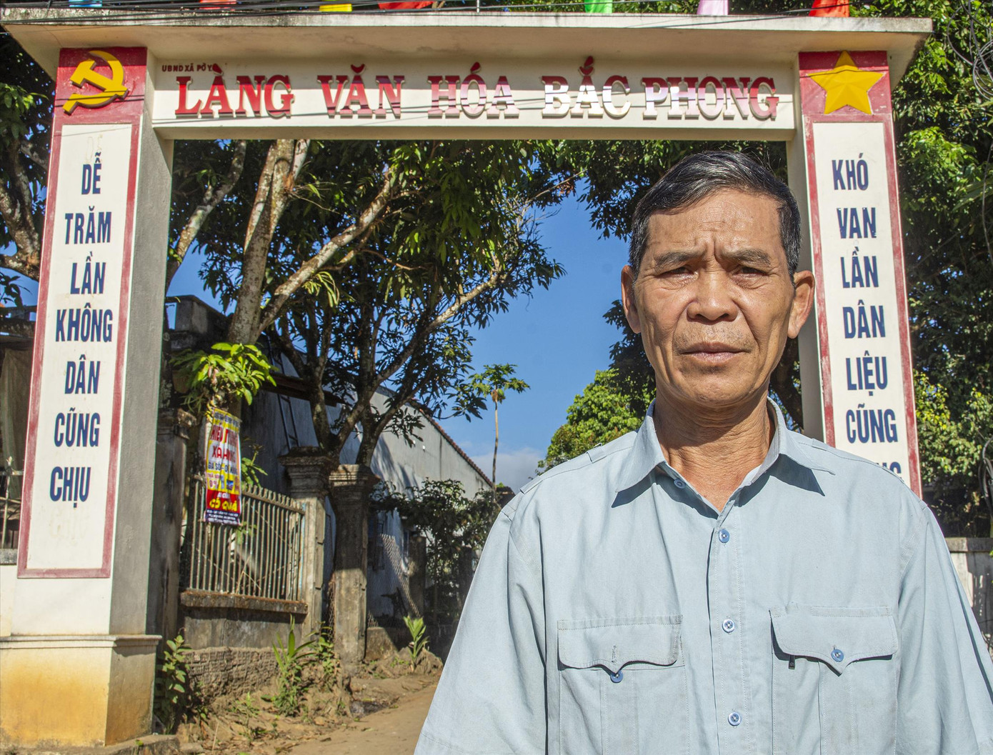 Ông Xa Văn Khoa, Bí thư chi bộ thôn Bắc Phong trước cổng làng người Mường ở vùng ngã ba Đông Dương. Ảnh: Văn Chương. Ông Xa Văn Khoa, Bí thư chi bộ thôn Bắc Phong trước cổng làng người Mường ở vùng ngã ba Đông Dương. Ảnh: Văn Chương.