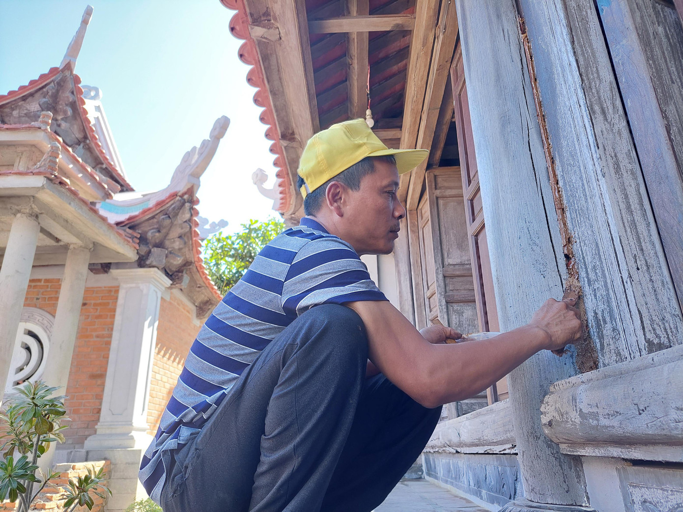 Anh Thao trám lại các mạch gỗ bị nứt tại chùa đảo Sơn Ca. Ảnh: Trần Tuấn