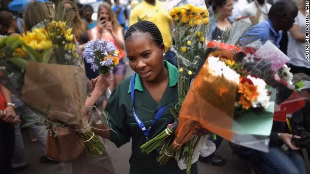 Người phụ nữ này thu những bó hoa của khách viếng thăm tại nhà ông Mandela.