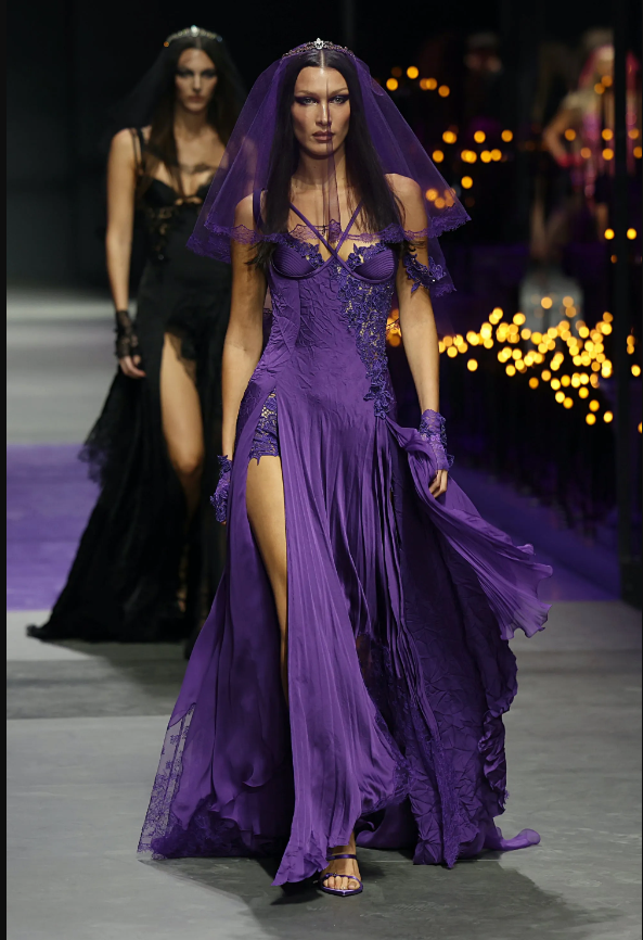 Chiếc váy Bella Hadid mặc có đường xẻ chân cao đặc trưng của Versace, những chi tiết trang trí bằng ren. Bella Hadid trông giống như một cô dâu mặc đơn giản mà đầy ma lực.