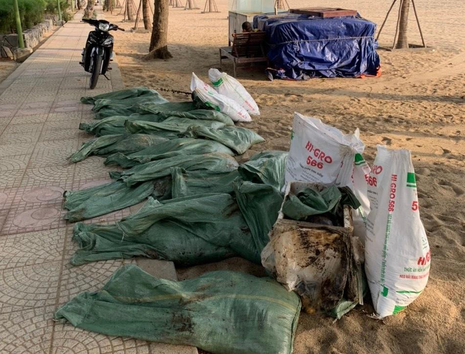 Công nhân môi trường thu dọn dầu vón cục tại bãi biển Nha Trang. Ảnh L.H