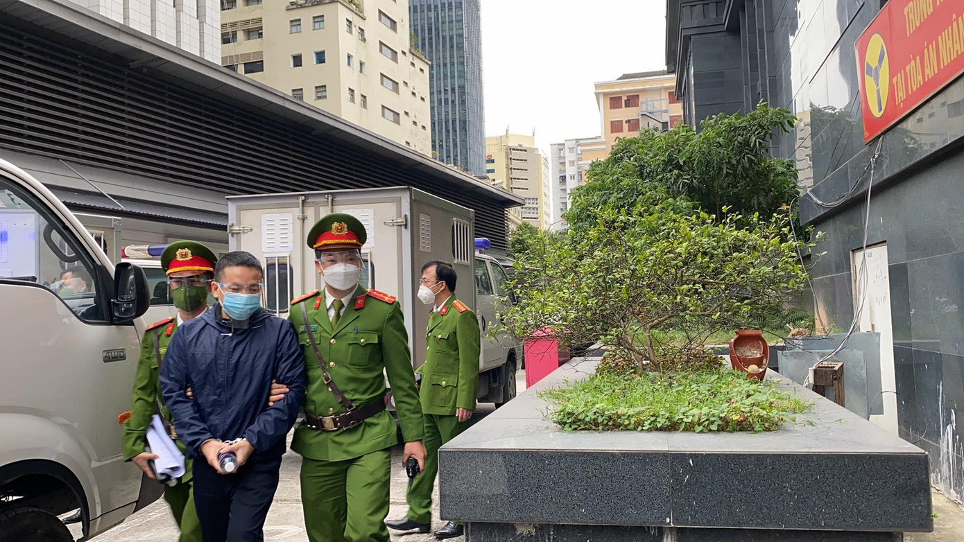 Lực lượng chức năng dẫn giải các bị cáo tới toà. Ảnh: N.C Lực lượng chức năng dẫn giải các bị cáo tới toà. Ảnh: N.C