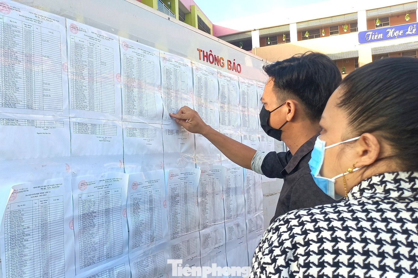 Phụ huynh dò tìm tên con trong danh sách học sinh được dán tại bảng thông báo của trường