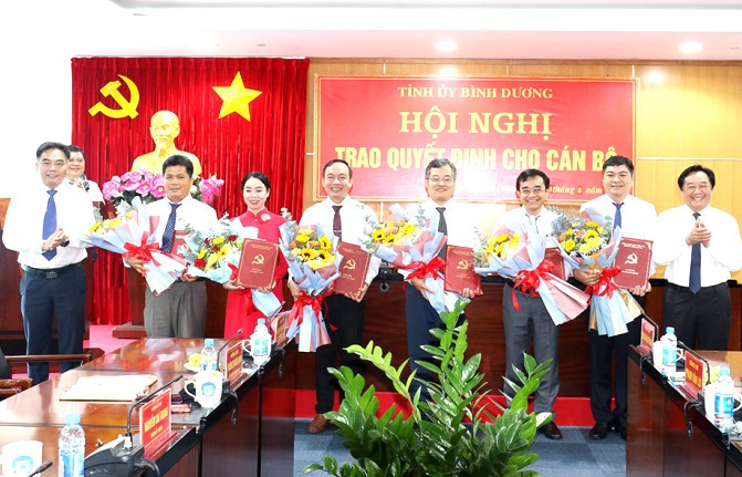 Phó Bí thư Thường trực Tỉnh ủy Bình Dương Nguyễn Hoàng Thao (ngoài cùng bìa phải) và Phó Chủ tịch UBND tỉnh Bình Dương Nguyễn Lộc Hà (ngoài cùng bìa trái) trao quyết định và tặng hoa cho các cán bộ được điều động, bổ nhiệm. Ảnh: Mai Xuân