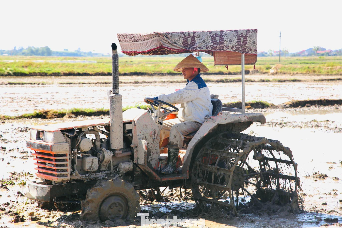 Người nông dân phải dùng chăn, che phần mái của máy để giảm bớt sức nhiệt.