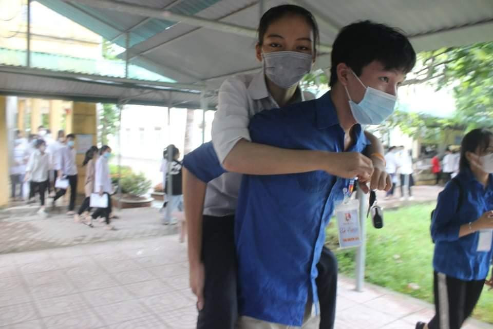 Bạn tình nguyện viên cõng thí sinh bị khuyết tật sau khi rời khỏi phòng thi.