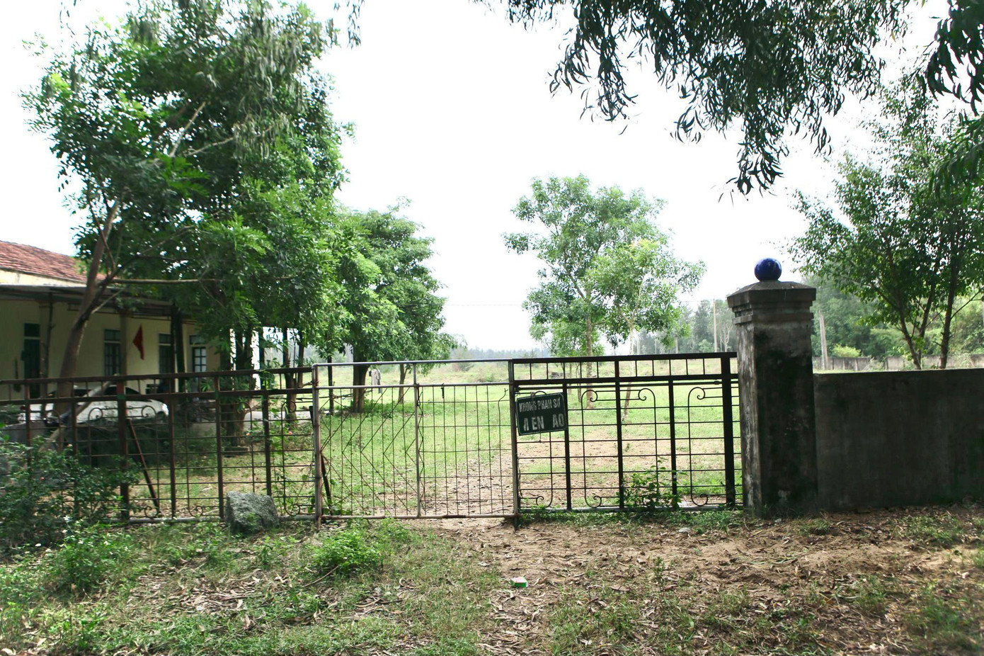 Cổng chính đóng cửa, tường bao xây xung quanh rêu mốc. Chỉ có hai người được giao nhiệm vụ bảo vệ khu vực trại.