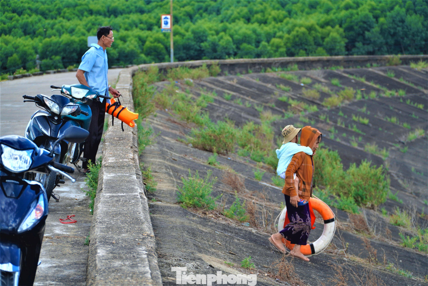 Dòng người di chuyển đến hồ Kẻ Gỗ để tắm lúc chiều tối rất đông. Khoảng thời gian từ 17-18h30’ là khoảng thời gian người dân đến tắm tại hồ đông nhất. Có người đi ô tô, cũng có người đi xe máy theo từng đoàn. Trong ảnh người bà cõng cháu xuống hồ để tắm.