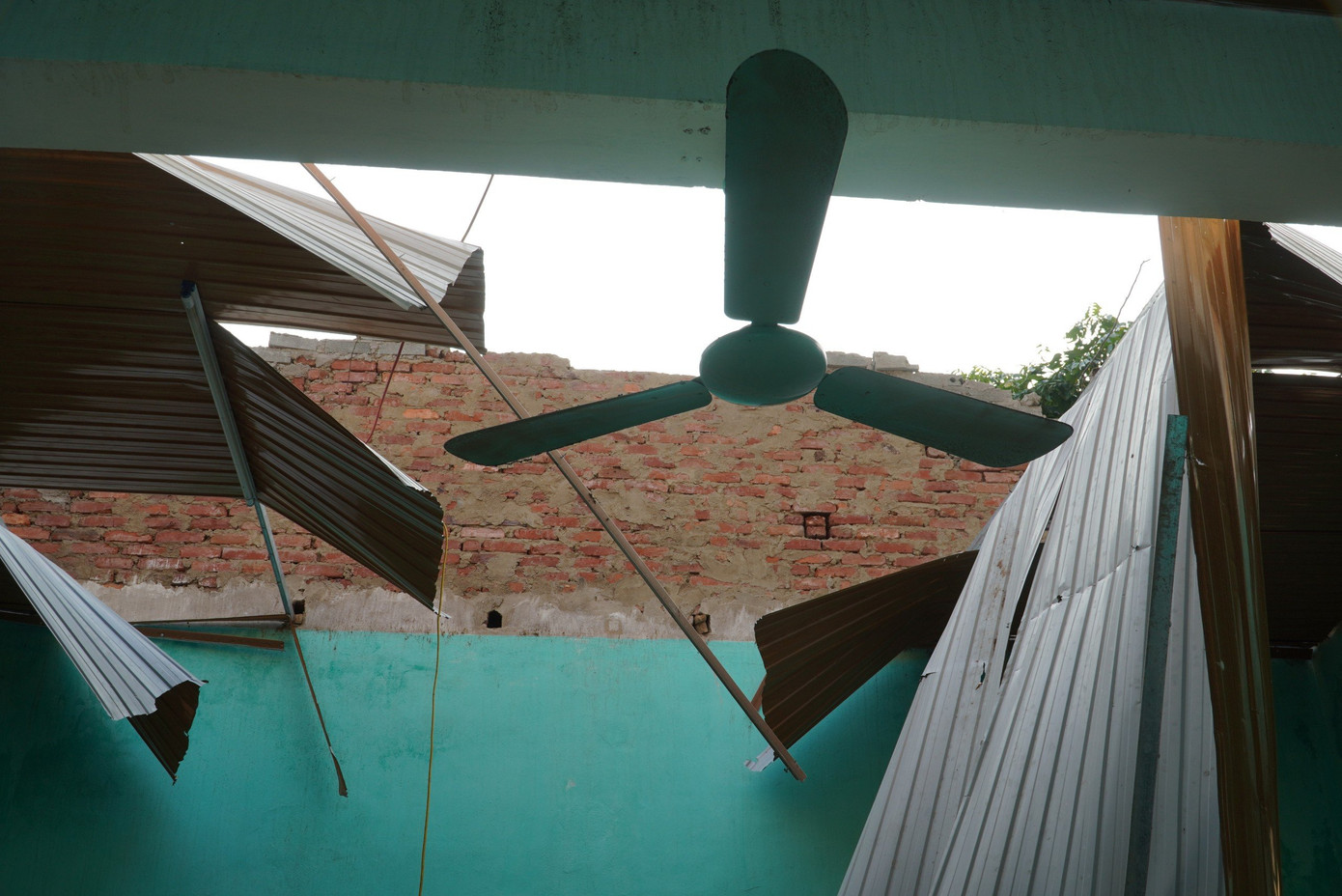 Mái tôn và phần trần nhà bị lốc xoáy làm gãy, để lại cảnh màn trời chiếu đất. Mái tôn và phần trần nhà bị lốc xoáy làm gãy, để lại cảnh màn trời chiếu đất.