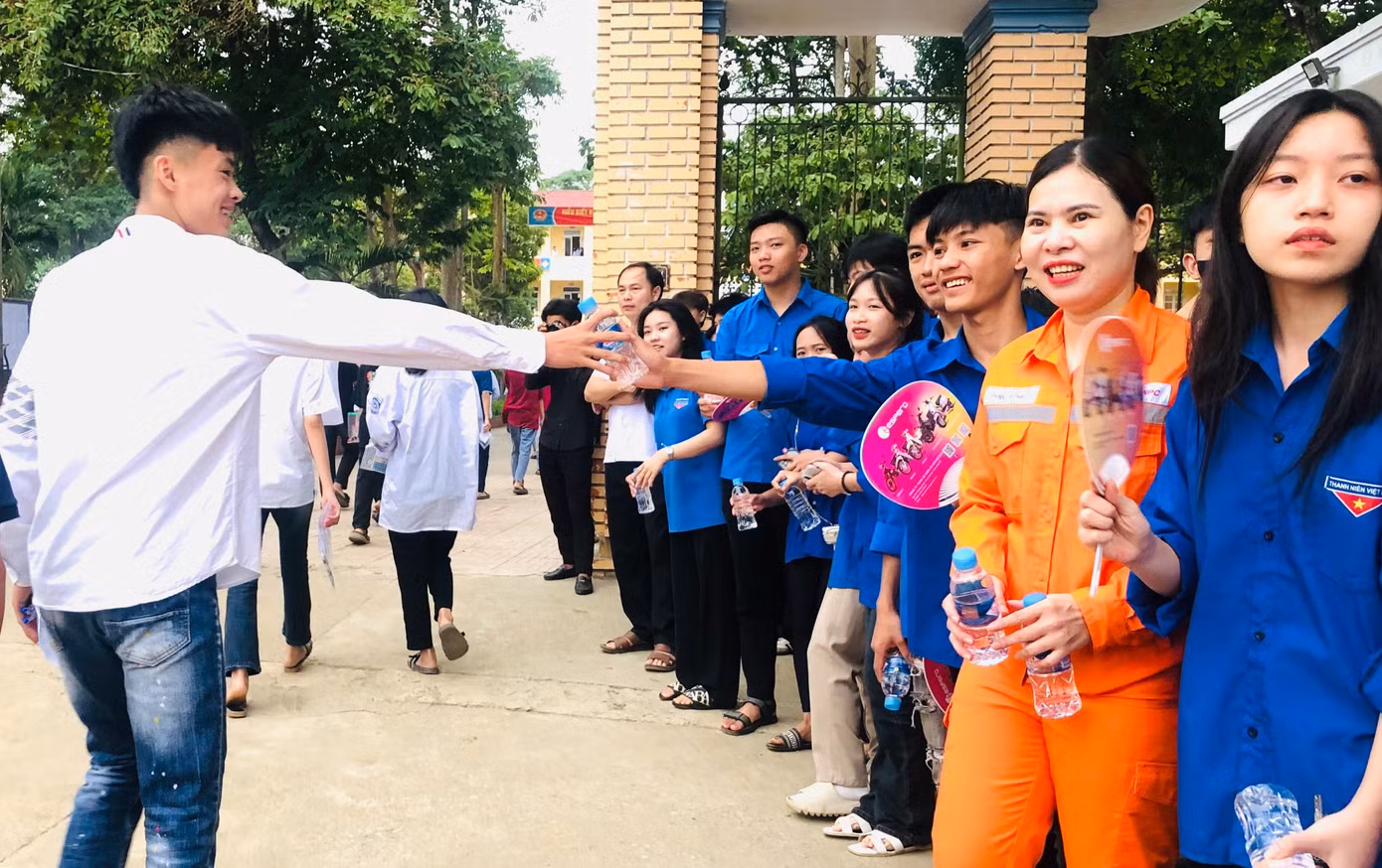 Phía ngoài cổng trường, thanh niên tình nguyện đã có mặt, cầm theo nước, sữa, quạt, bánh ngọt để hỗ trợ các thí sinh sau buổi thi.