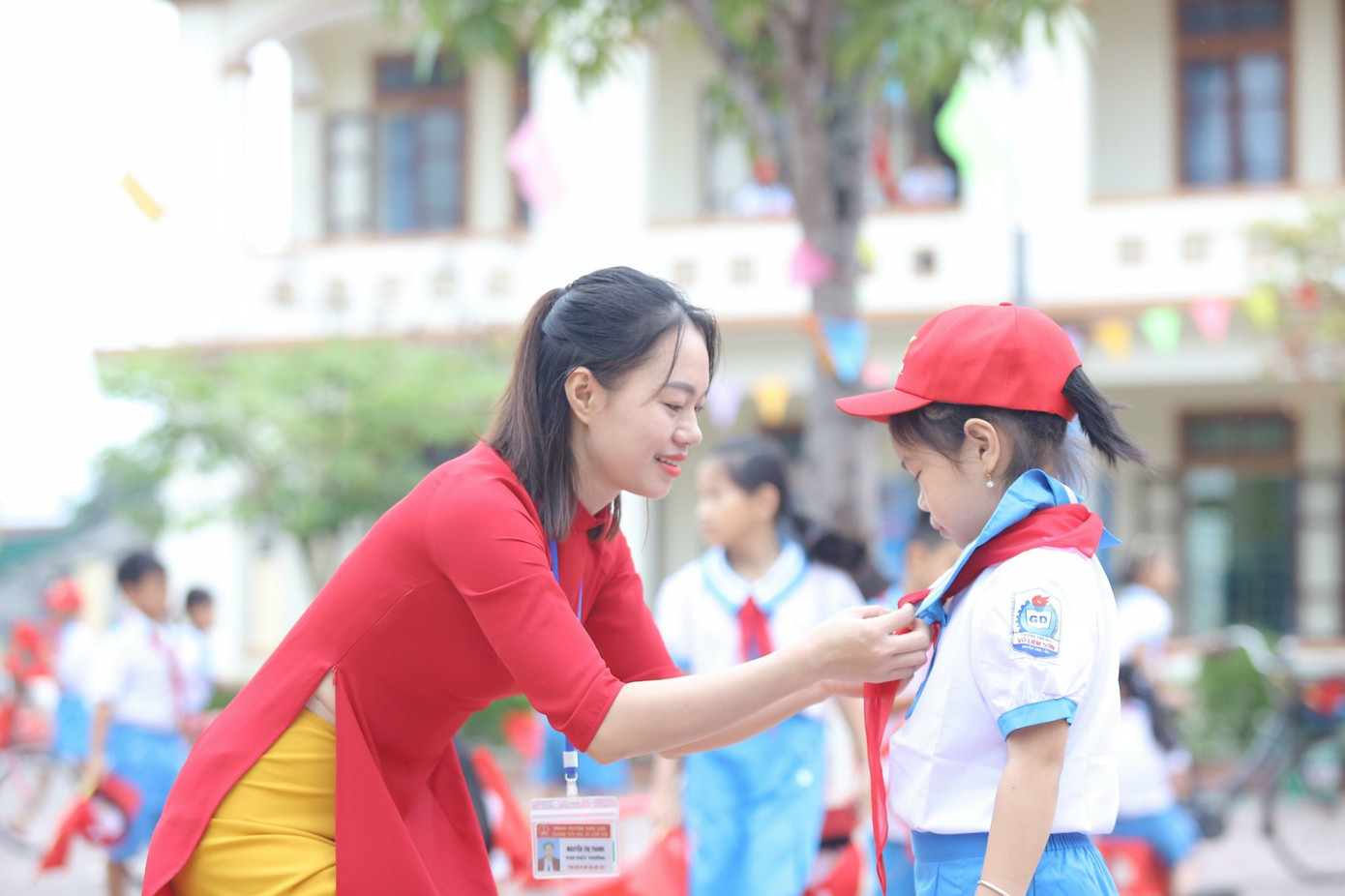 Các cô giáo thướt tha trong tà áo dài truyền thống nắm tay các em vào trường, đeo khăn quàng đỏ cho học sinh trong ngày khai giảng.