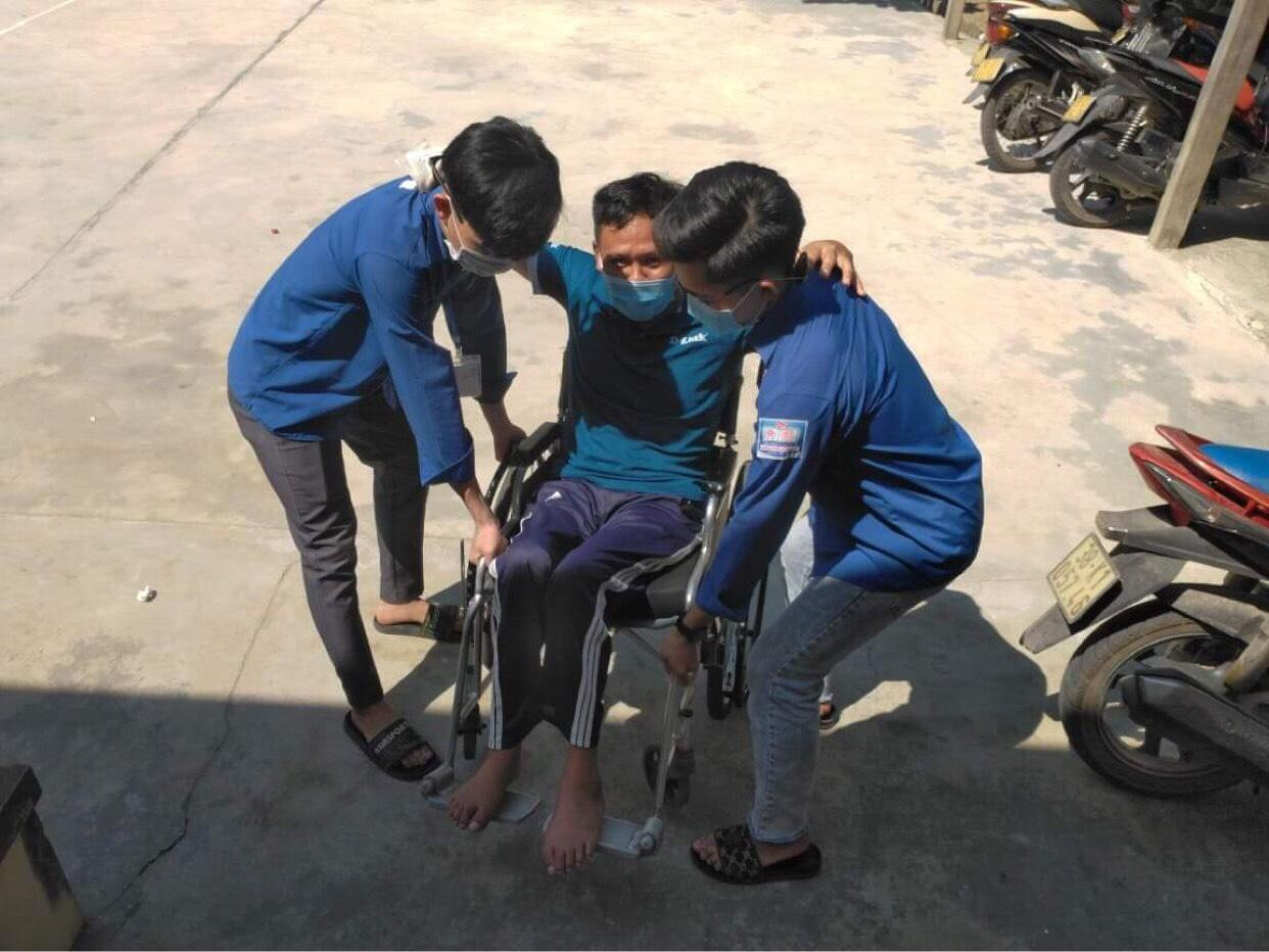 Hai bạn tình nguyện viên hỗ trợ cử tri ngồi xe lăn vào phòng bầu cử bỏ phiếu.