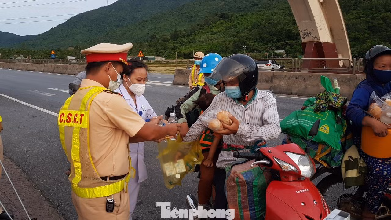 Cảnh sát hỗ trợ bánh, nước uống cho người dân di chuyển bằng xe máy về quê tại điểm chốt cửa ngõ Hà Tĩnh.
