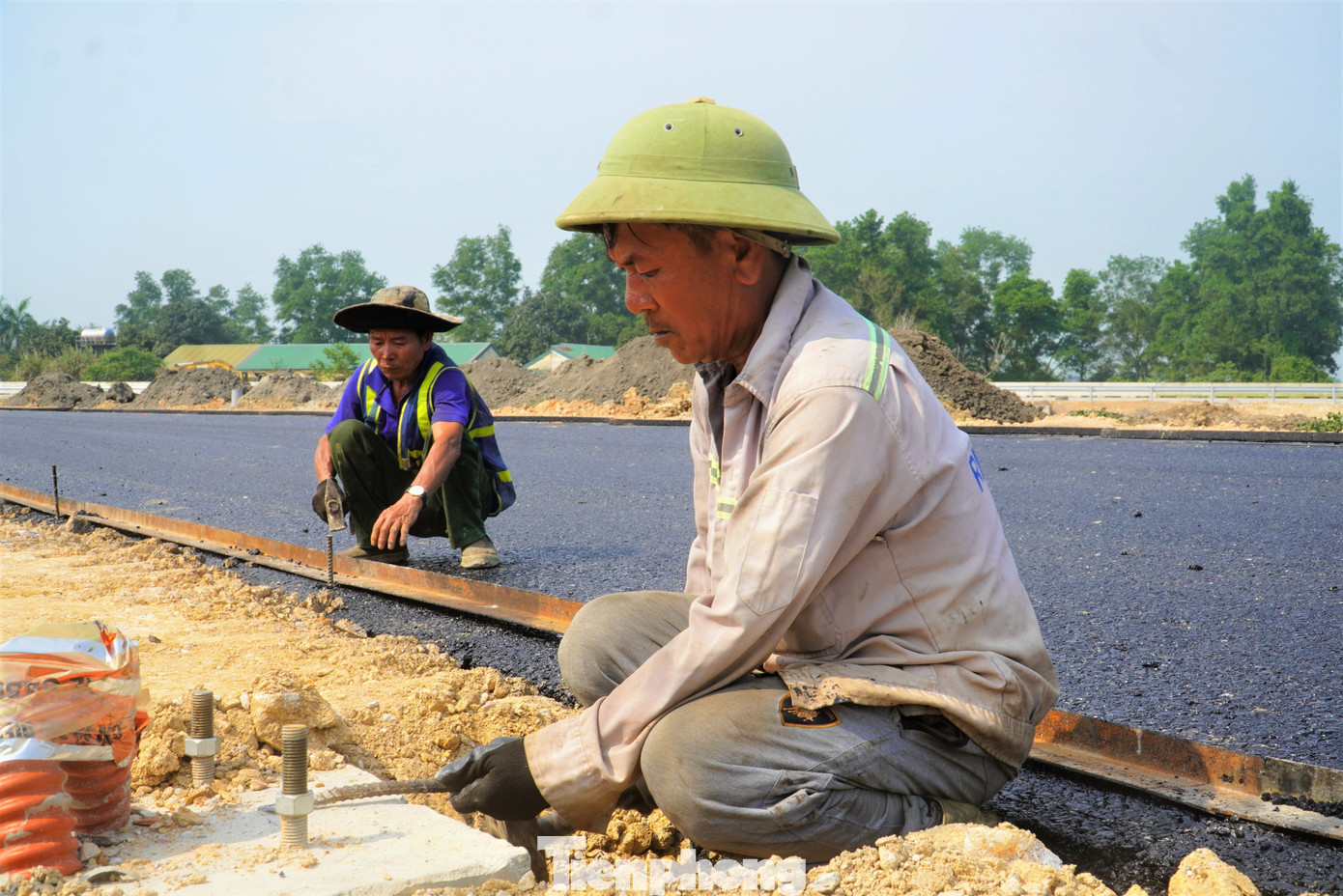 Những thảm lớp bê tông nhựa cuối cùng đang được công nhân hoàn thiện.