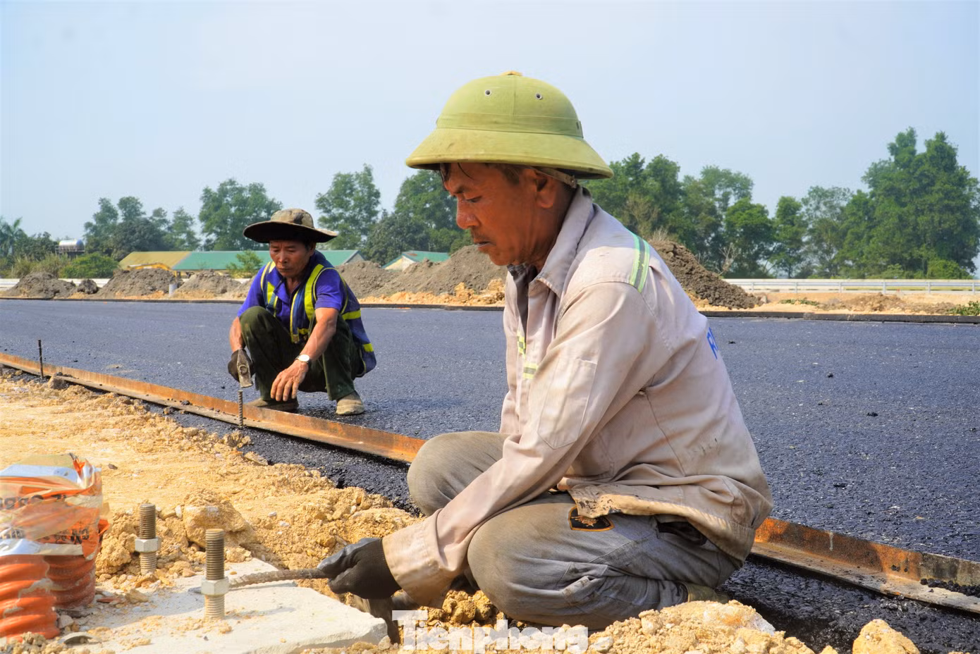 Những thảm lớp bê tông nhựa cuối cùng đang được công nhân hoàn thiện.