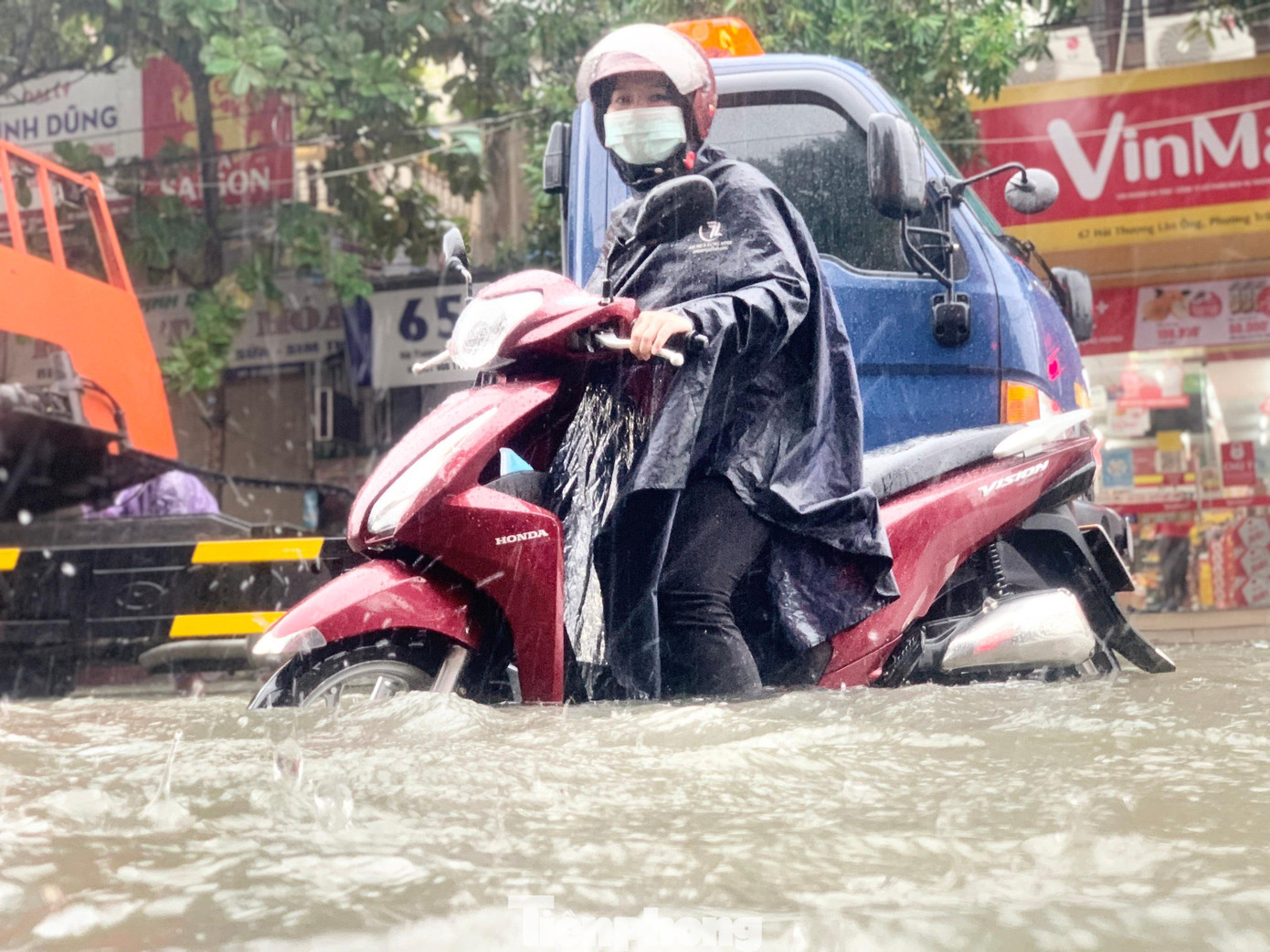 Nước ngập lút bánh xe khiến chiếc xe máy của người phụ nữ bị chết máy giữa đường.