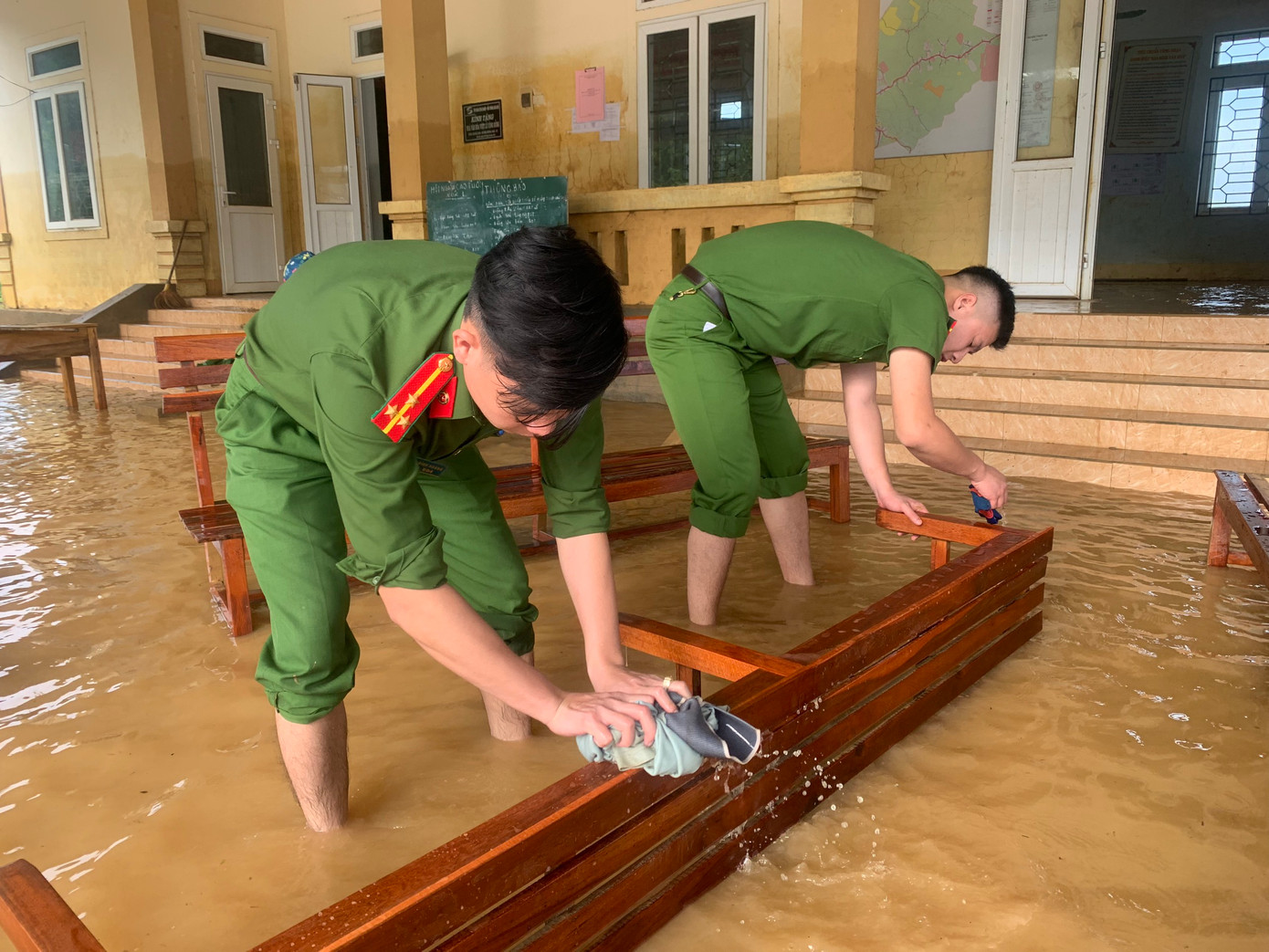Chiến sĩ công an lau chùi bàn ghế bị ngập lụt.
