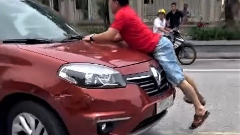 Người đàn ông bám nóc capo xe đang chạy để chặn ô tô va chạm. (Hình ảnh cắt từ clip)