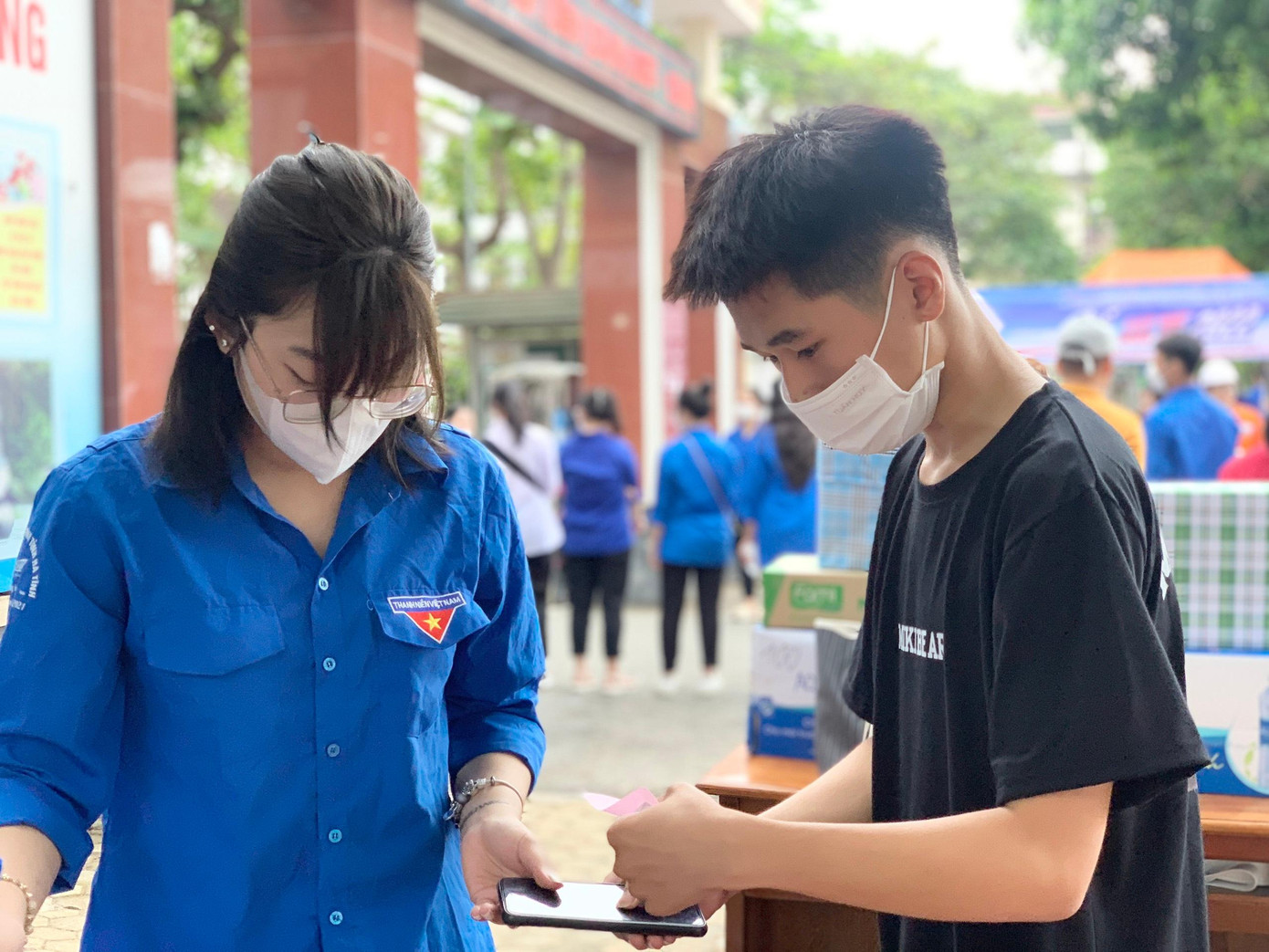 Tại cổng trường, các thí sinh nhờ các tình nguyện viên cất giữ điện thoại trước khi vào phòng thi.