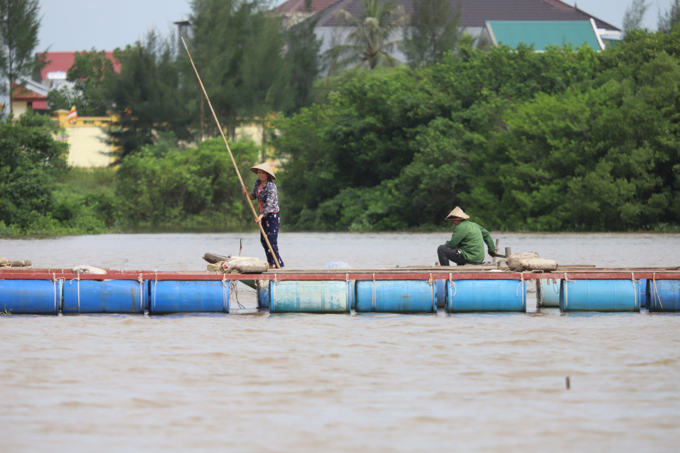 Đôi vợ chồng ở xã Thạch Hạ (TP Hà Tĩnh) đang di chuyển cá lồng bè vào vị trí an toàn.
