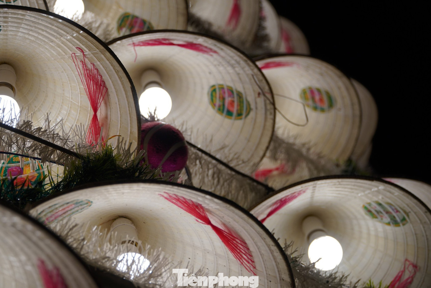 Ở mỗi chiếc nón được trang trí bóng đèn, quấn dây kim tuyến và trang trí thêm quả cầu đủ sắc màu. Nón được lắp đặt theo khuôn cây thông đã cố định sẵn.