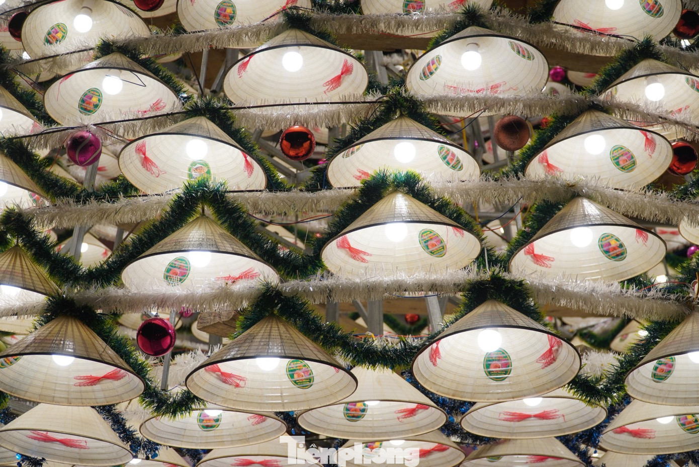 Ở mỗi chiếc nón được trang trí bóng đèn, quấn dây kim tuyến và trang trí thêm quả cầu đủ sắc màu. Nón được lắp đặt theo khuôn cây thông đã cố định sẵn.