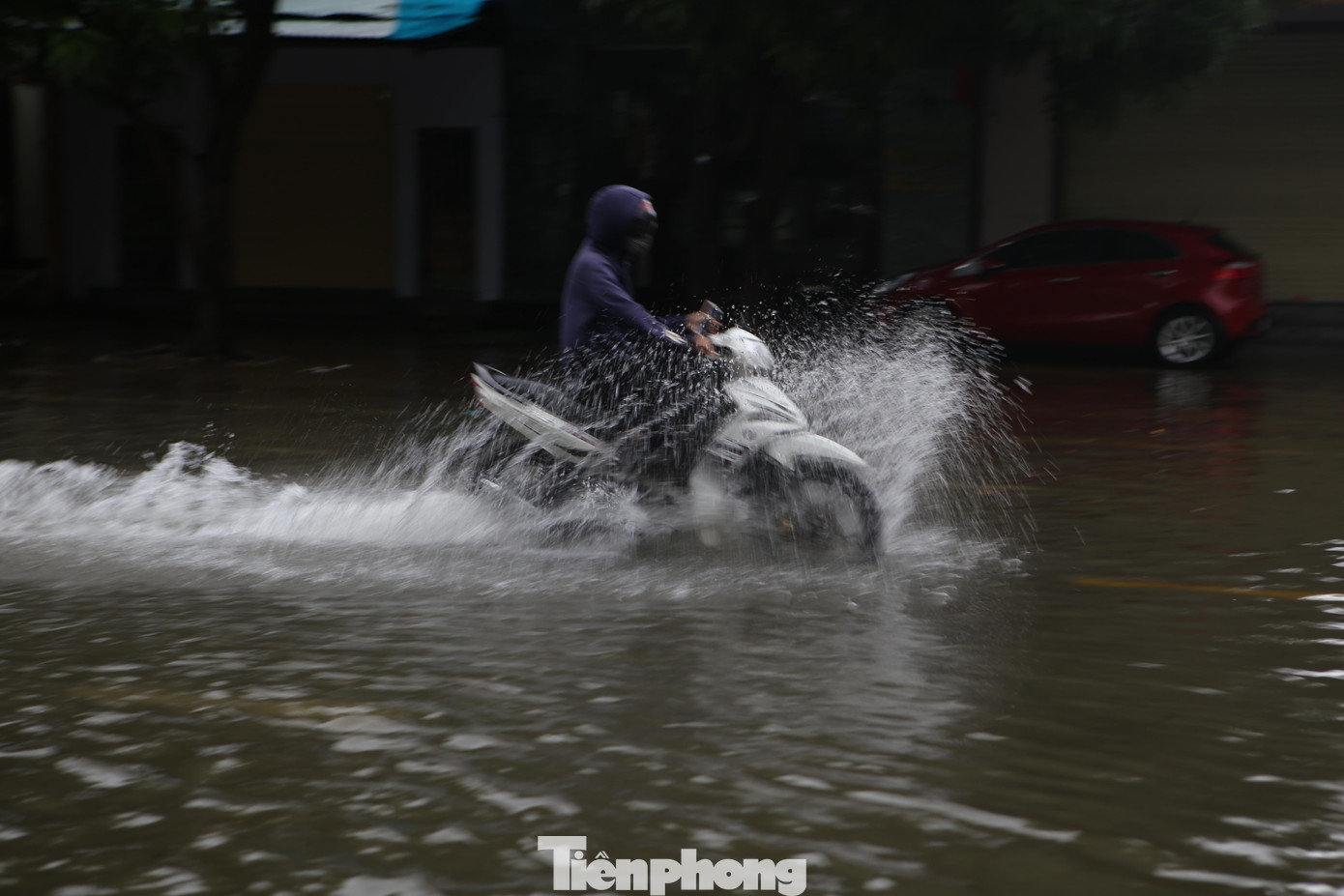 Nhiều người dân băng qua dòng nước để đi làm. Một số tuyến đường bị ngập, nhưng xe máy vẫn có thể di chuyển qua.