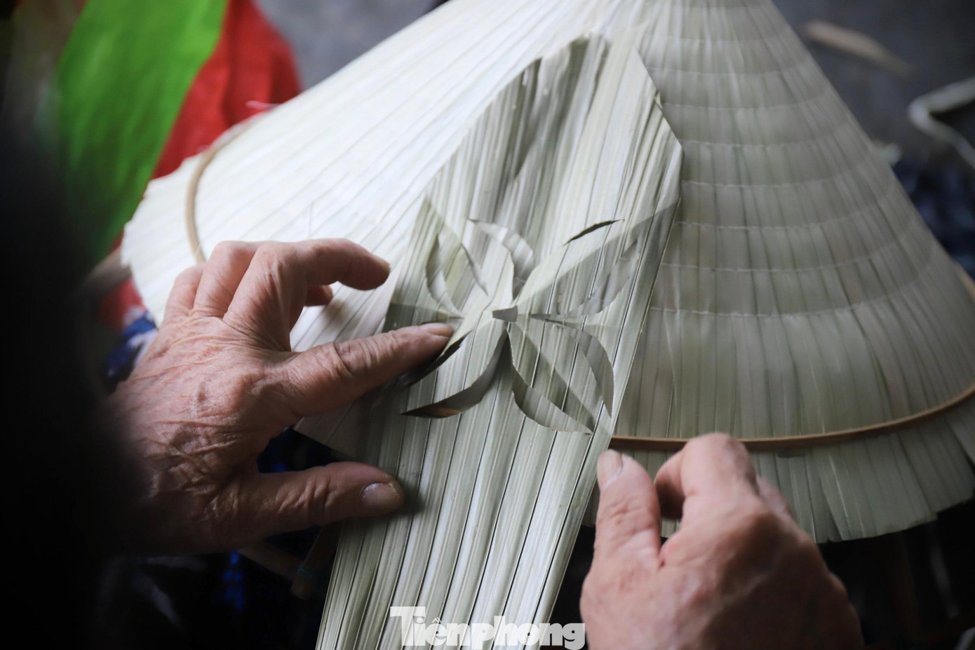 Người thợ dùng lá màu xanh để cắt hoa bốn cánh, sau đó kết hoa vào lớp lá thứ hai rồi dùng lớp lá trắng phía ngoài che lại.