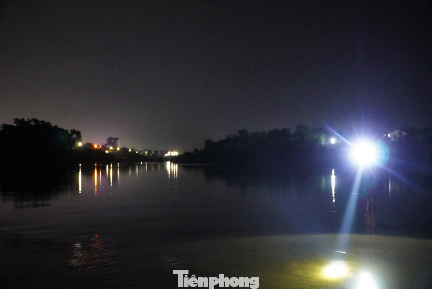 Dọc bờ sông, ánh sáng yếu ớt từ ánh đèn pin của người dân đi bắt cá.