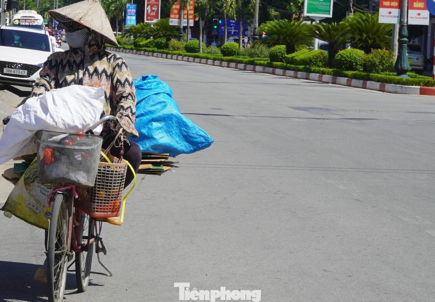 Gần trưa, đường phố vắng bóng người. Trên những con đường, sức nóng từ mặt nhựa đường hầm hập phả vào mặt. Trong ảnh, người phụ nữ đạp xe len qua từng ngõ ngách để nhặt ve chai.