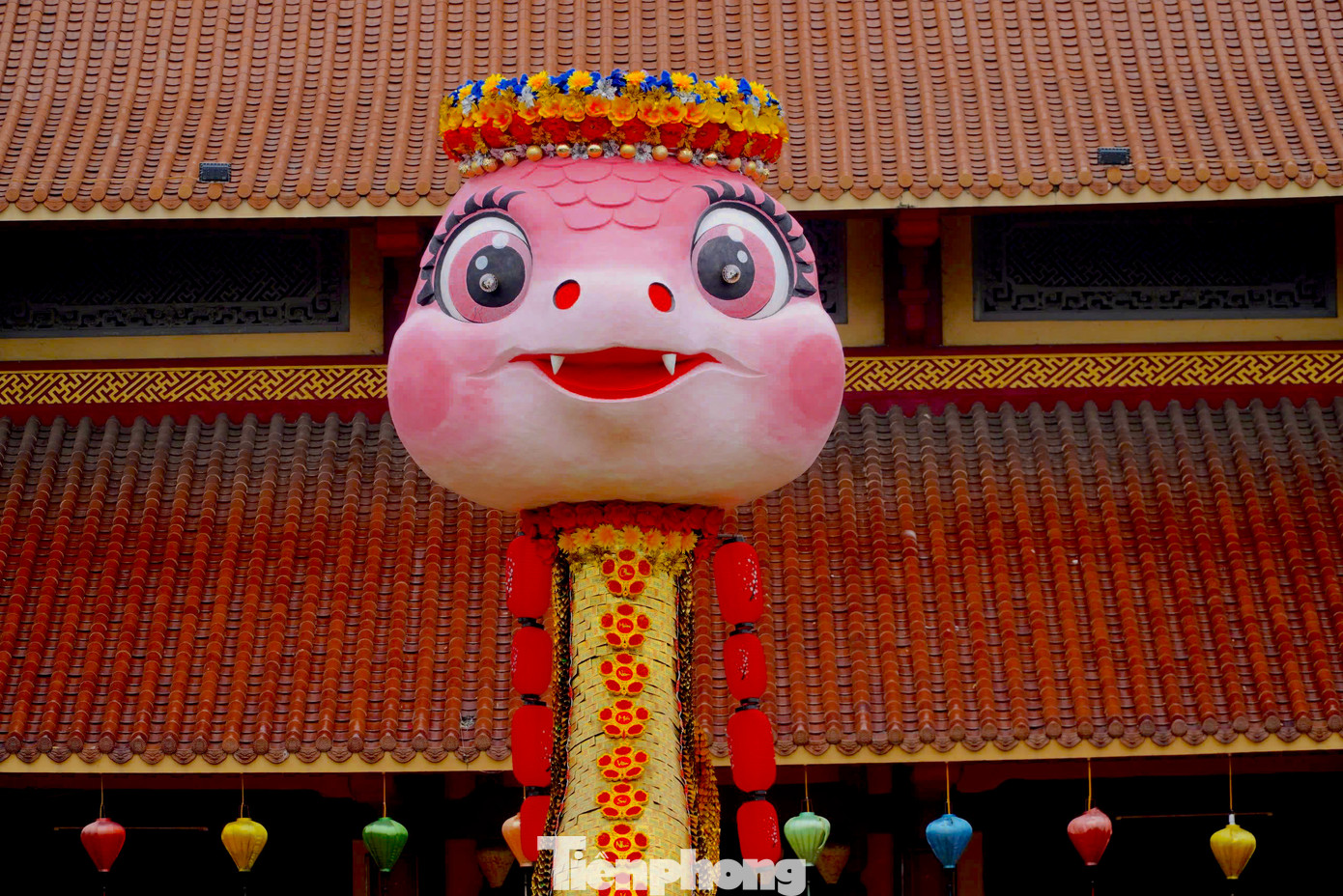 Phần đầu linh vật màu hồng, mắt long lanh, đội vòng hoa.