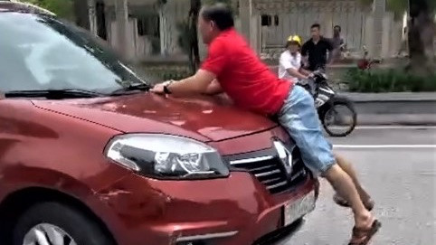 Người đàn ông bám đầu ôtô đang chạy ở TP Hà Tĩnh. Ảnh: Cắt từ clip