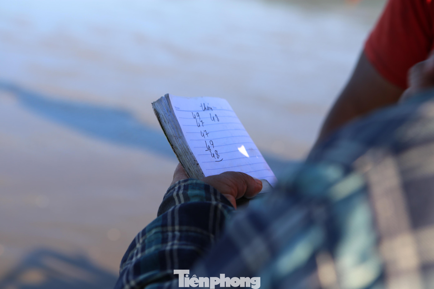 Thương lái ghi sổ tường khay hàng đựng ruốc được đưa vào bờ để thanh toán cho chủ thuyền.