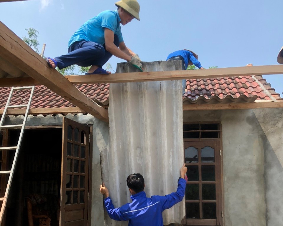 Thanh niên mỗi người một nhiệm vụ, người chuyền gạch, người quét dọn, người leo mái nhà lợp lại mái để giúp người dân ổn định chỗ ở.
