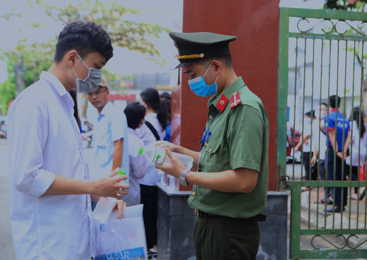 Nam sinh mang chai nước có nhãn mác vào cổng, cảnh sát đã hỗ trợ gỡ nhãn mác để đưa vào phòng thi theo đúng quy định.