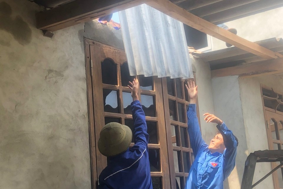 Đoàn viên thanh niên "đội nắng" hỗ trợ giúp người dân tu sửa lại nhà cửa sau khi lốc xoáy cuốn bay nhiều mái nhà.