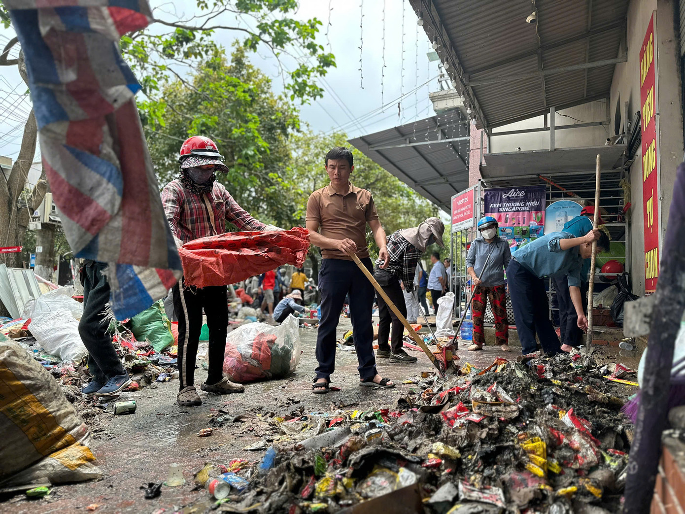 Nhiều người hỗ trợ chủ cửa hàng thu gom đồ đạc, dọn dẹp sau đám cháy.