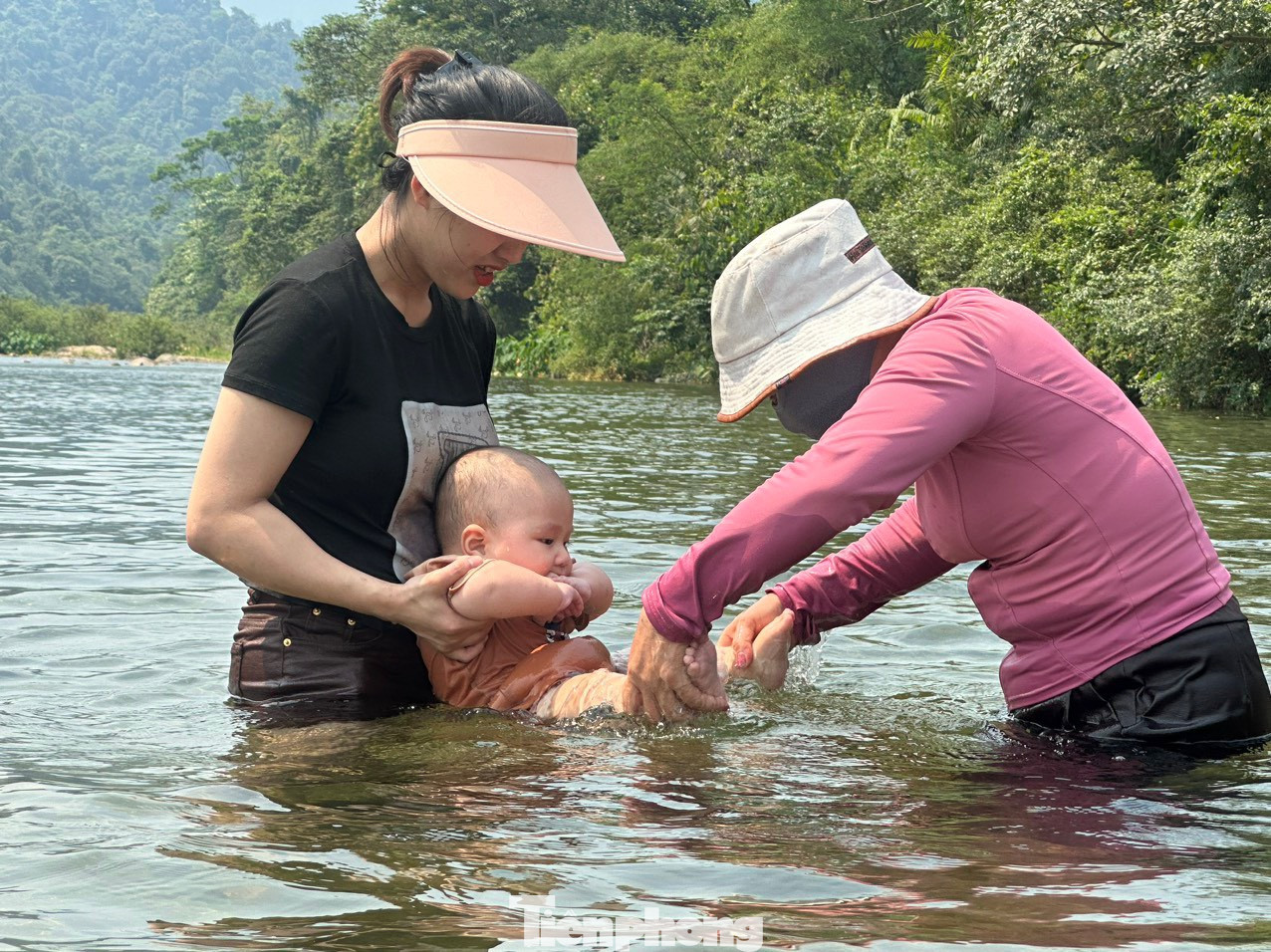 Em bé gần 12 tháng tuổi được mẹ đưa đến khe suối để tắm mát trong ngày hè oi bức.