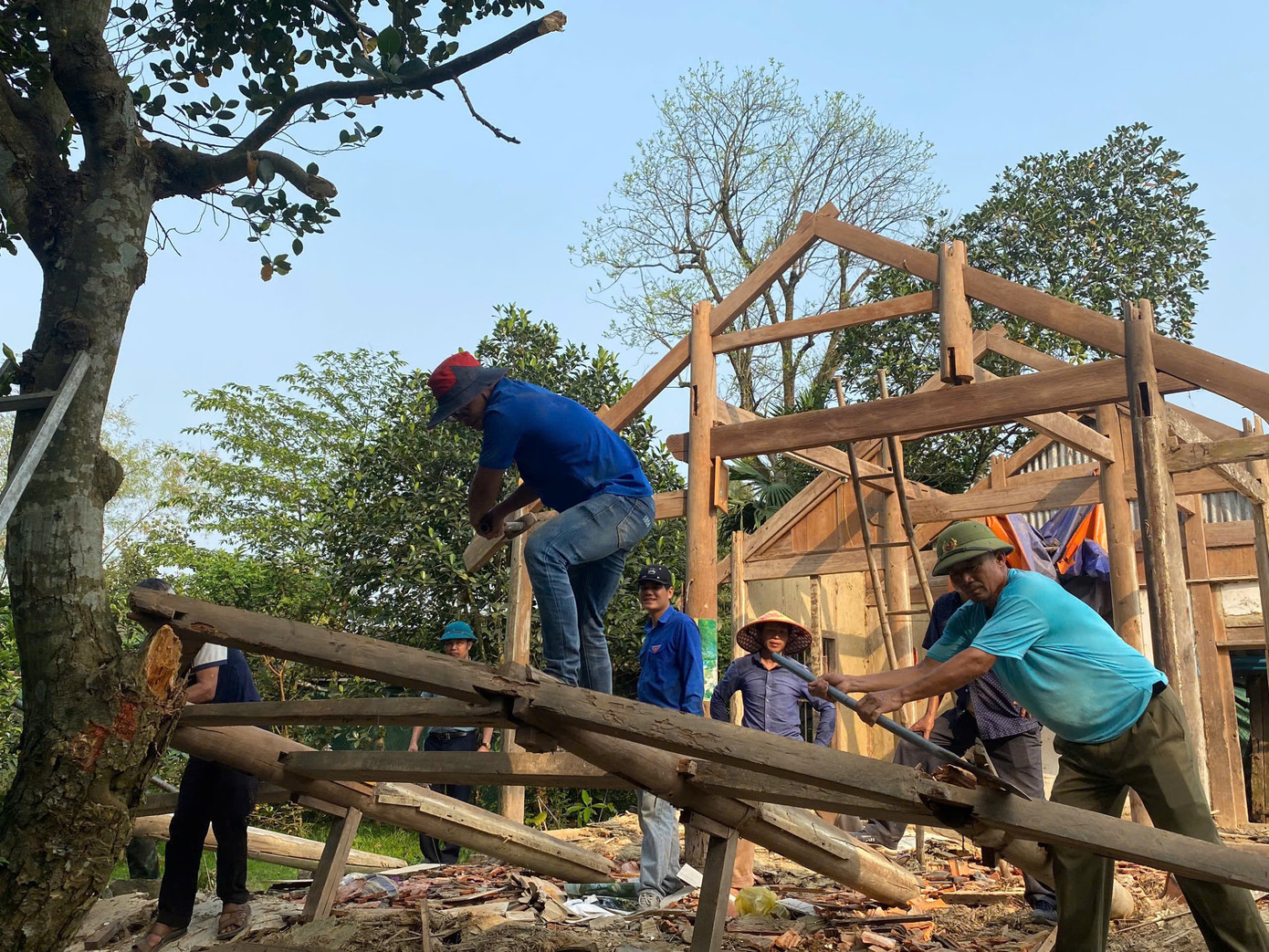 Sau khi giải phóng mặt bằng, thanh niên nhanh nhẹn thu dọn phần mái nhà cũ, san nền, vận chuyển vật liệu. Dù công việc khá vất vả, nhưng các bạn trẻ không nề hà vất vả để giúp gia đình bà Thiêm đẩy nhanh tiến độ xây dựng nhà ở.