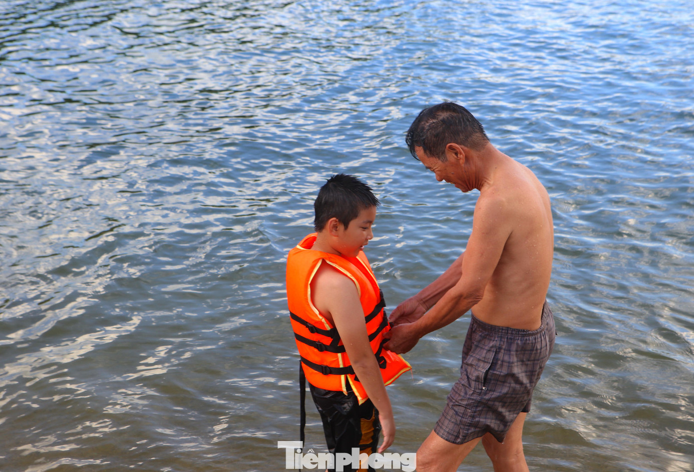 Trước khi xuống hồ tắm, trẻ em được người thân mặc áo phao để tập bơi.