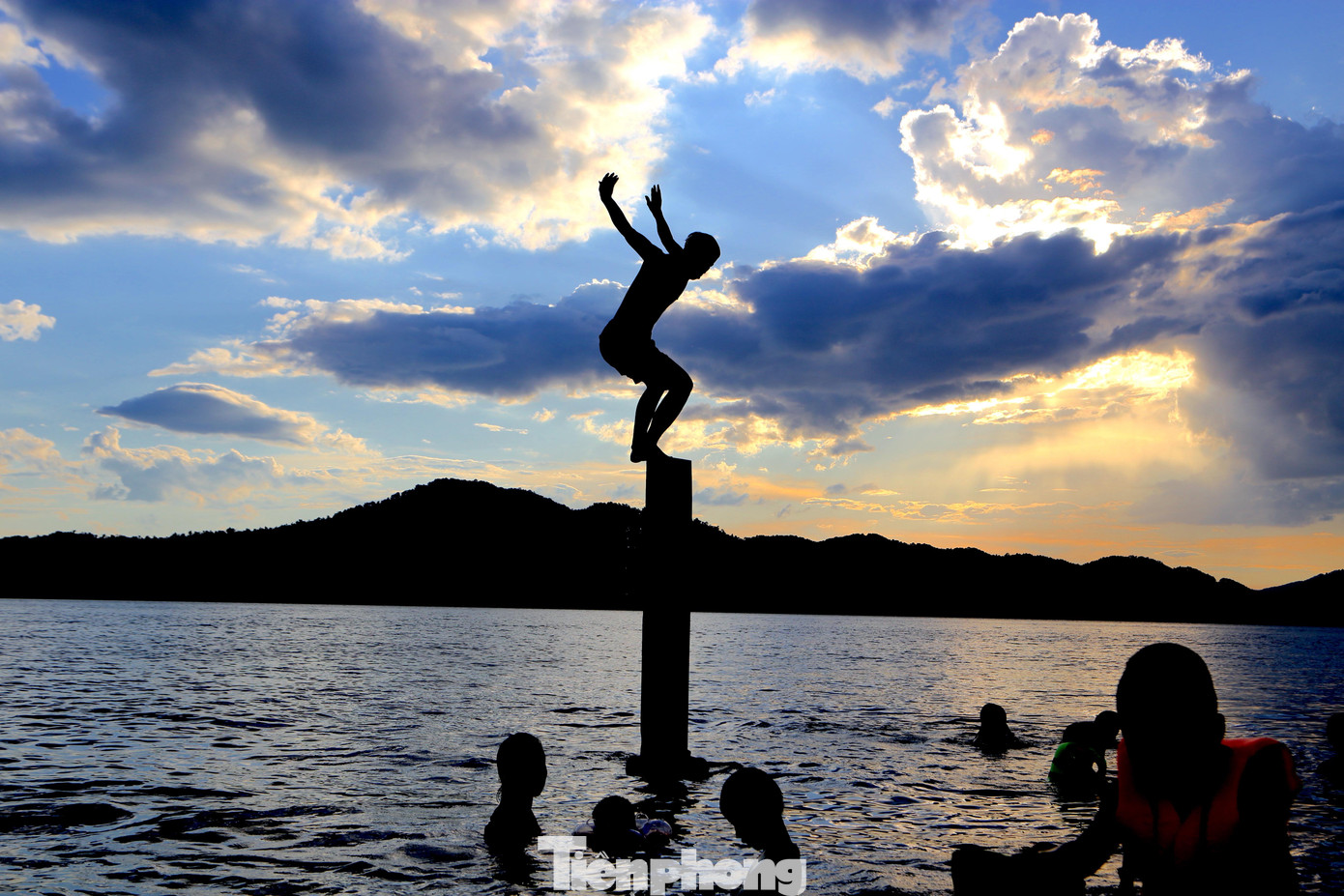 Nhiều người đưa con nhỏ ra tắm, cho con tập bơi ở gần bờ. Một số thanh niên, thiếu niên đứng tại các khối bê tông để nhào lộn xuống hồ.