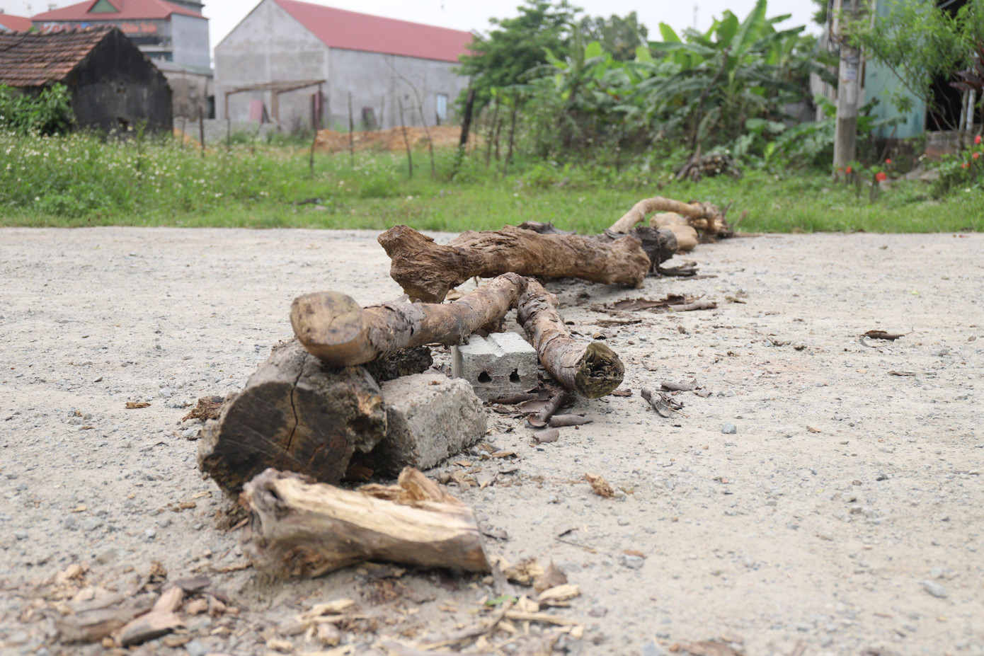 Do số lượng xe lưu thông nhiều, gây bụi bặm, người dân ở thị xã Kỳ Anh (Hà Tĩnh) đã rải đá, chèn gỗ để ngăn để hạn chế ô tô chạy nhanh.