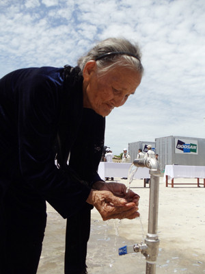 Bà Võ Thị Ta hứng dòng nước mát tại máy lọc nước