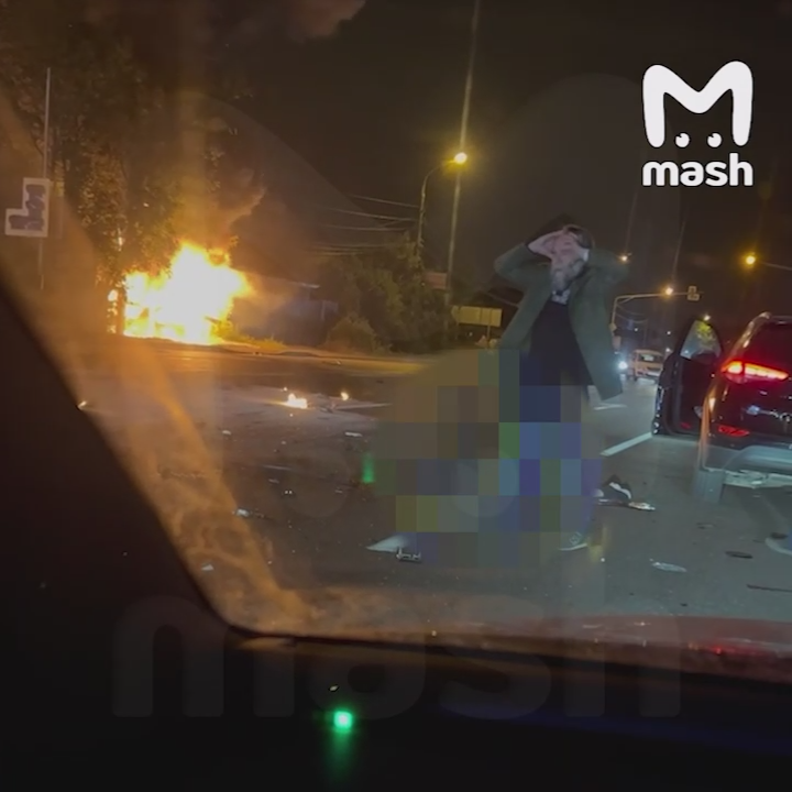 Ông Dugin tại hiện trường vụ tai nạn. Phía xa là chiếc xe hơi đang bốc cháy phừng phừng. Ảnh: Mash