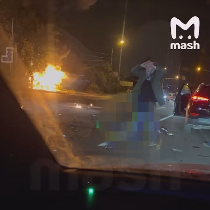 Ông Dugin tại hiện trường vụ tai nạn. Phía xa là chiếc xe hơi đang bốc cháy phừng phừng. Ảnh: Mash